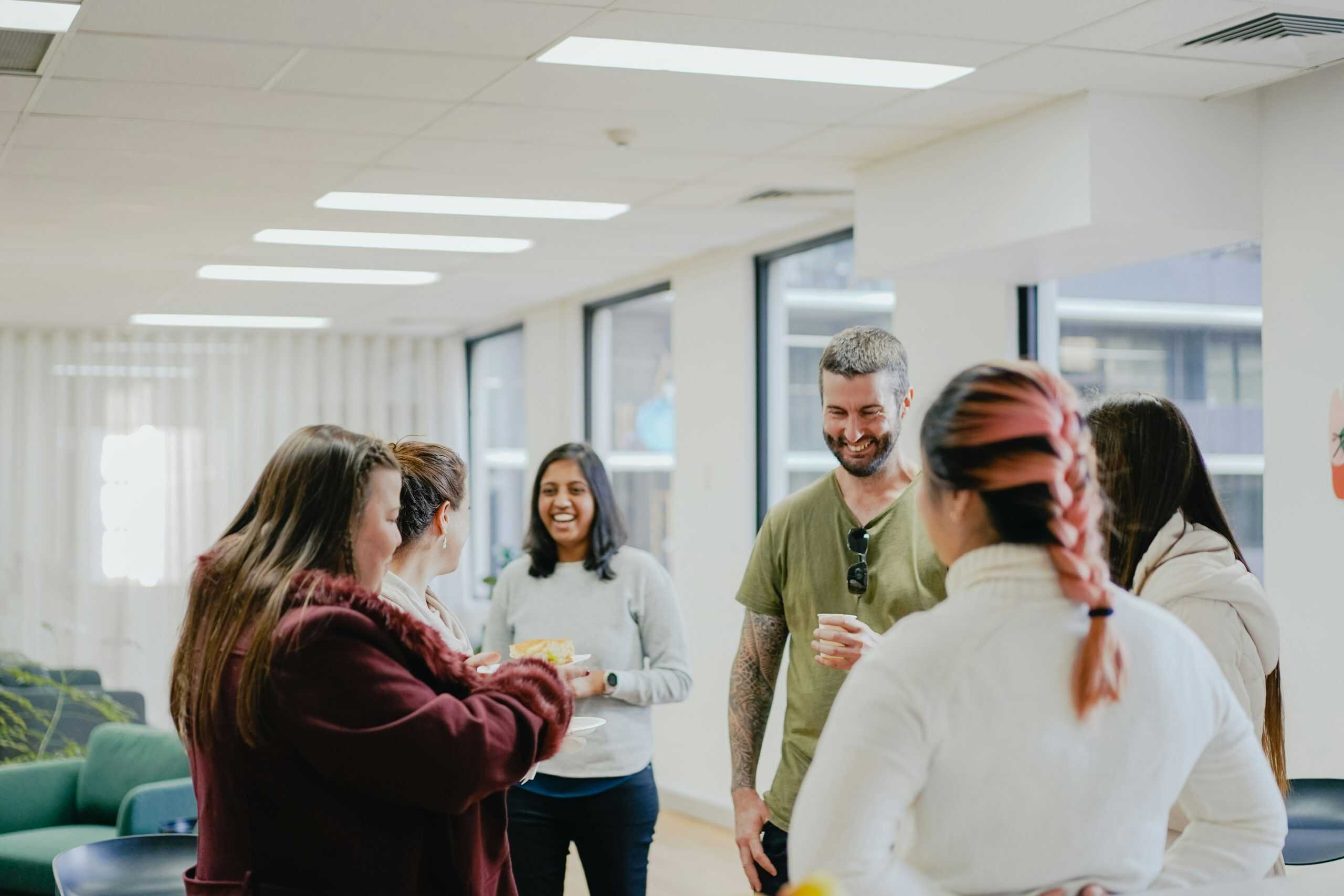 A group of people at work smiling and feeling the benefits of employee engagement