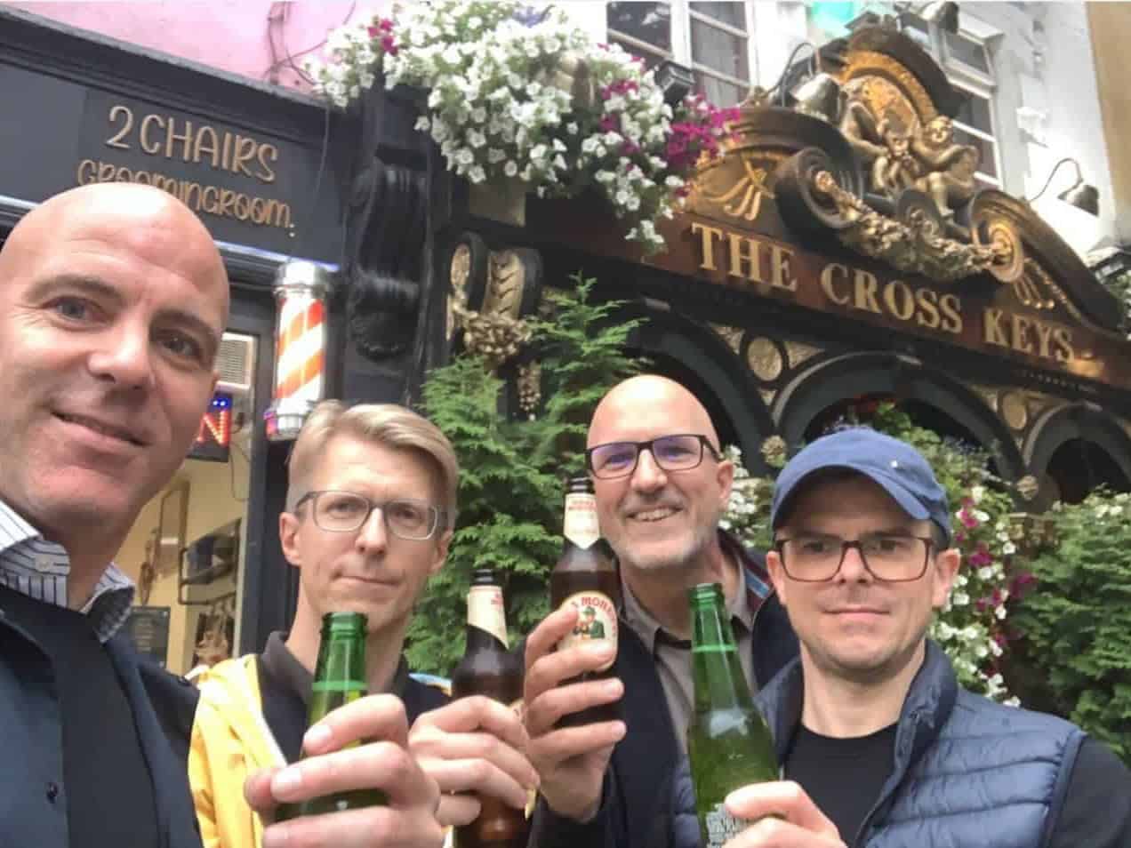 A team of men raising their drinks outside the cross keys pub in London