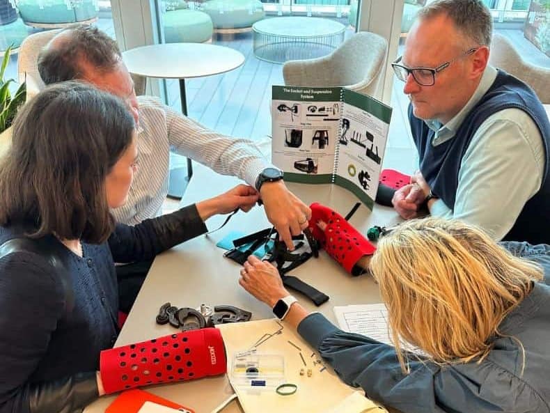 A team working together to build a prosthetic hand for developing countries as part of charity team building activity